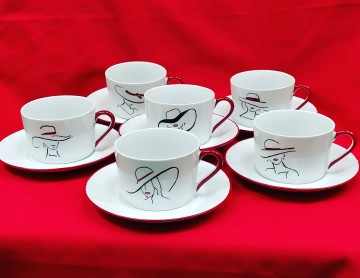 cette photo montre un service à thé en porcelaine décoré avec des visages féminins stylisés en noir et rouge